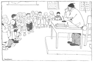 Ein Mann in Schuhen sitzt an einem Schreibtisch mit Büchern und Gegenständen, einer Gruppe von Kindern gegenüber, mit Papieren an der Wand hinter ihm.