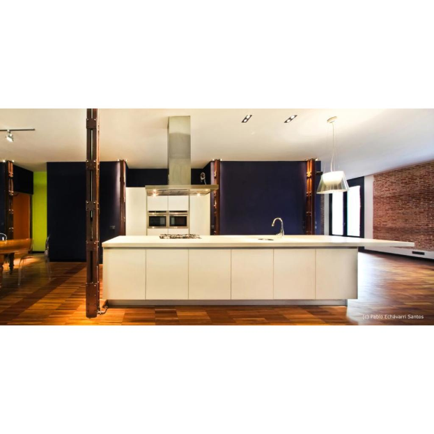 Eine Kücheninnenansicht mit einer weißen Plattform, Spüle, Kühlschrank, Schranktüren, schwarzer Wand, Hängelampe, brauner Ziegelwand, Glastür und Holzboden.