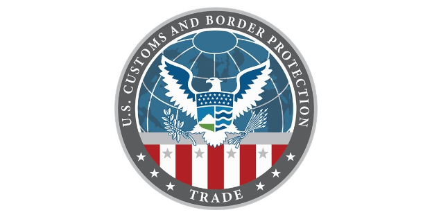 Logo des U.S. Customs and Border Protection Trade mit einem blauen Kreis mit einem weißen Stern, einer weißen Taube mit ausgebreiteten Flügeln und dem Text "U.S." über der Taube, alles innerhalb eines weißen Randes.