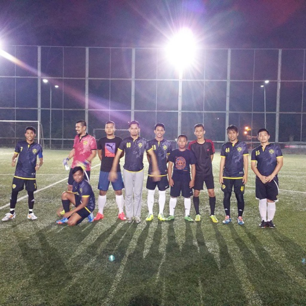 Ein Spielplatz mit mehreren Männern, die stehen, einem Jungen auf dem Knie eines Mannes und Laternen im Hintergrund.