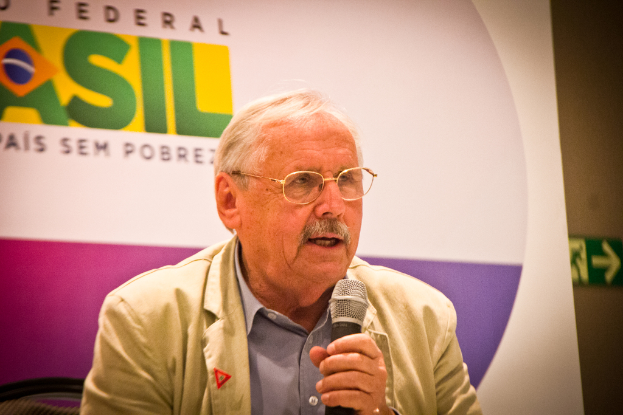 Eine Person, die in ein Mikrofon spricht und hinter ihr ein Banner mit der Aufschrift "Bundes" zu sehen ist.