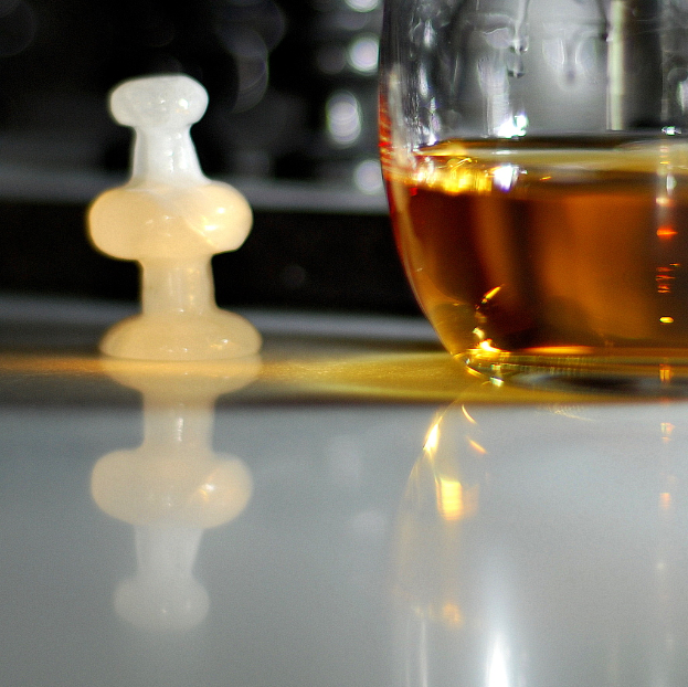 Ein Weinglas und ein weißes Schachstück sind auf einem Tischdecke platziert.