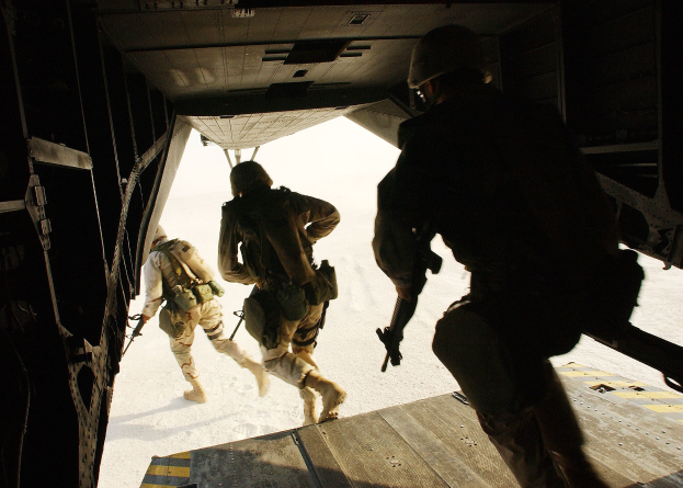 Soldaten in Uniform und Helmen, die ein Flugzeug verlassen und dabei Gewehre halten.