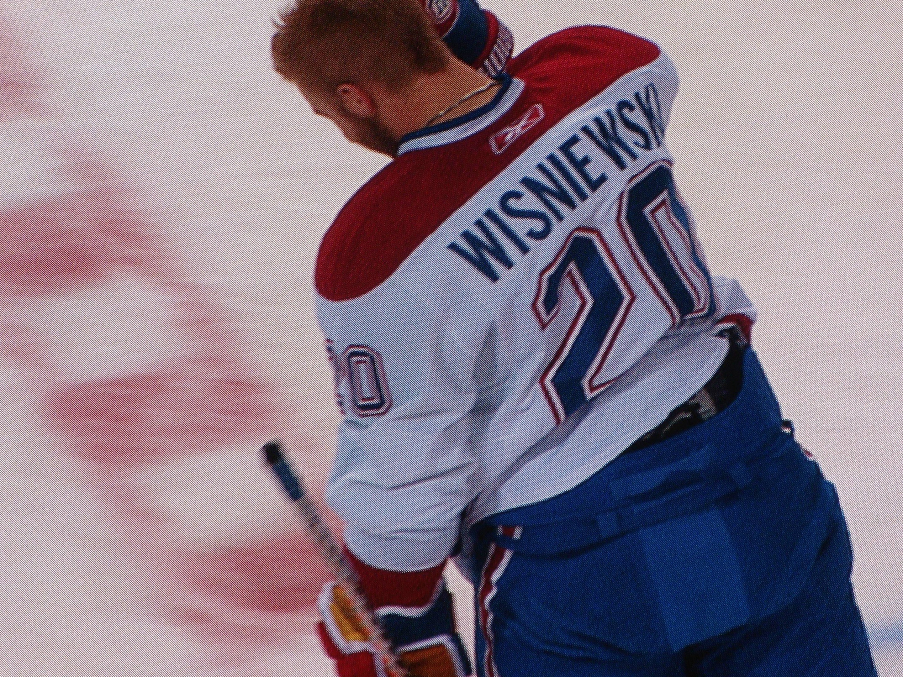 Professioneller Eishockeyspieler mit einem "Wisniewski"-Trikot, der einen Hockey-Schläger auf dem Eis hält, mit konzentrierter Miene.