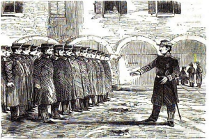 Ein Mann mit einer Mütze, der einen Stock hält, steht vor einer Reihe uniformierter Männer, im Hintergrund ist ein Gebäude mit Bögen und Fenstern zu sehen; unten steht der Text "Die Verhaftung von Charles Dickens".