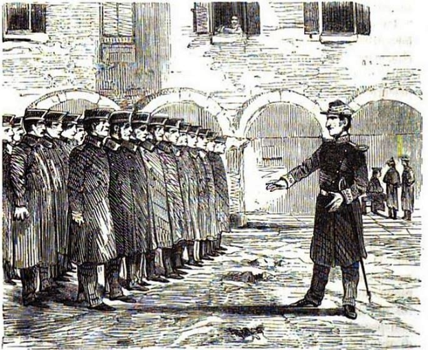 Ein Mann mit einer Mütze, der einen Stock hält, steht vor einer Reihe uniformierter Männer, im Hintergrund ist ein Gebäude mit Bögen und Fenstern zu sehen; unten steht der Text "Die Verhaftung von Charles Dickens".