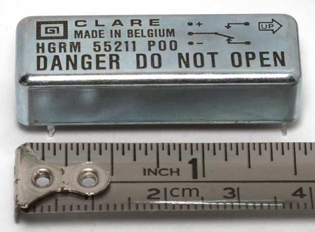 Metallbox beschriftet mit "Danger Do Not Open" neben einer Lineal auf einer weißen Oberfläche.