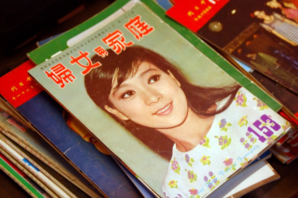 Eine Sammlung von Zeitschriften auf einem Tisch, wobei die vorderste Zeitschrift ein Bild einer Frau zeigt.