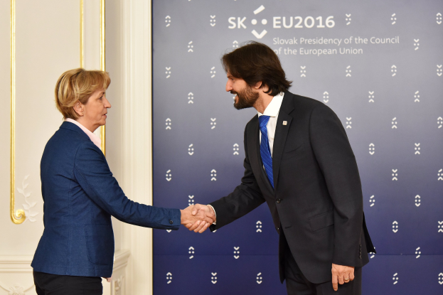 Bundeskanzlerin Angela Merkel und Bundeskanzler Joachim Gauck schütteln sich die Hände auf einem EU-Gipfeltreffen und lächeln beide.