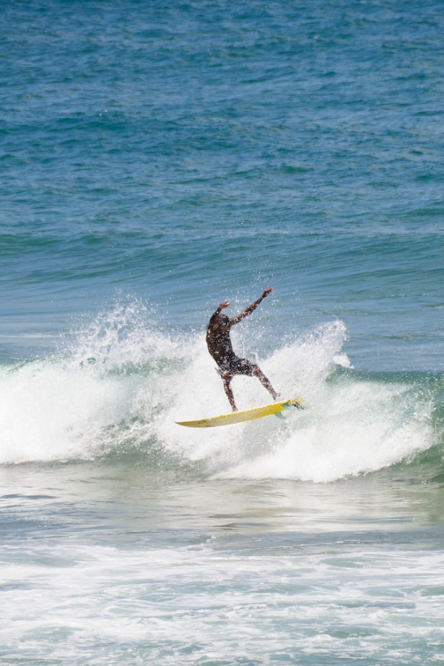 Ein Mann steht auf einem Surfbrett und reitet eine Welle im Wasser.