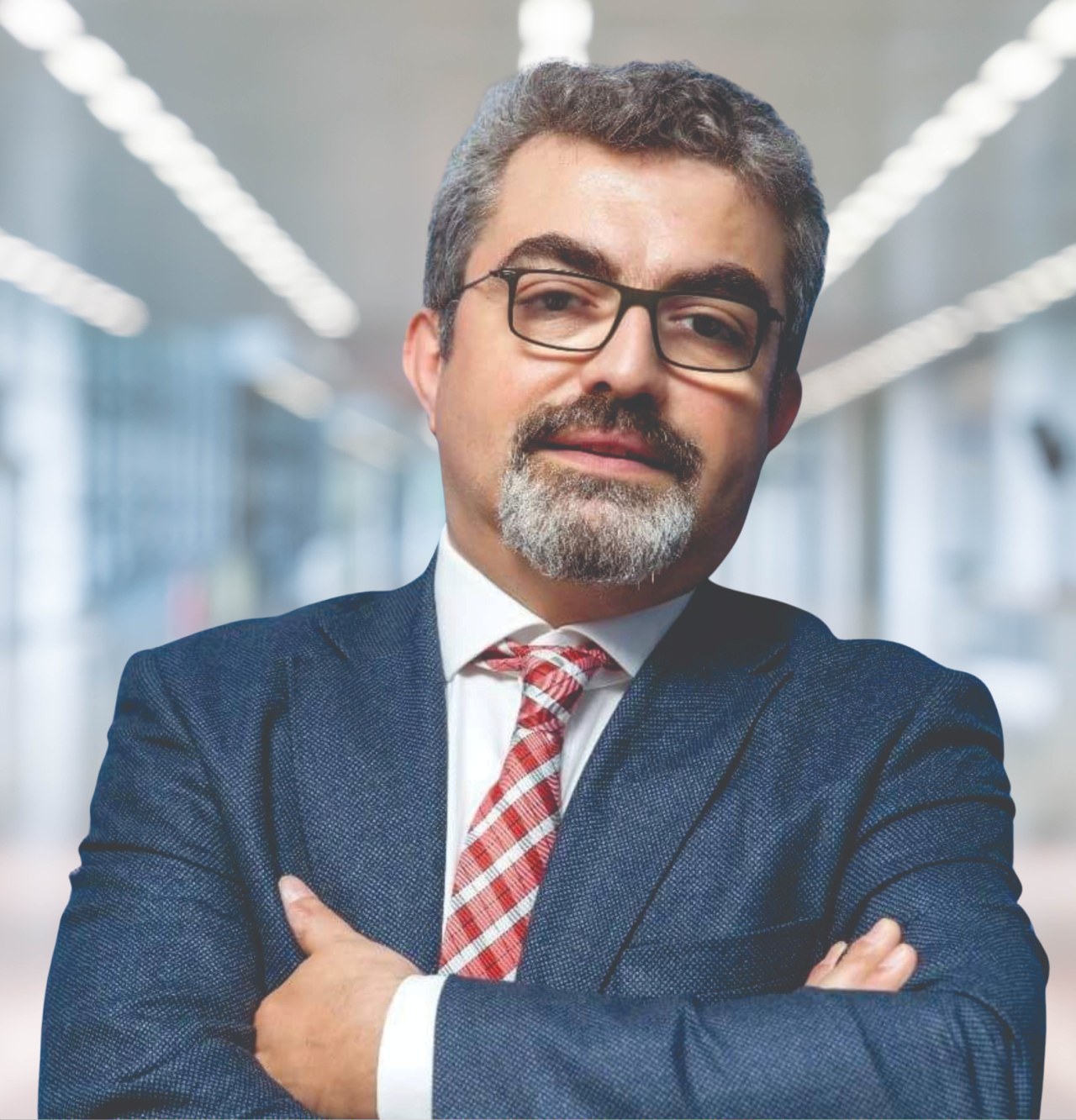 Ein Mann im Anzug und Krawatte mit verschränkten Armen, der eine Brille trägt und vor einem unscharfen Hintergrund steht, auf dem steht, dass er der neu ernannte Marketingchef ist.