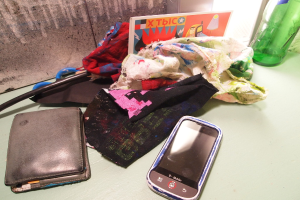 Tuchstücke, ein Handy und eine Geldbörse sind auf einer Oberfläche angeordnet.