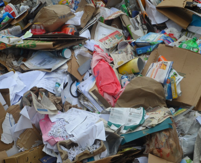 Ein Stapel Kartons mit verschiedenen Gegenständen wie Papieren, Flaschen und Abdeckungen.