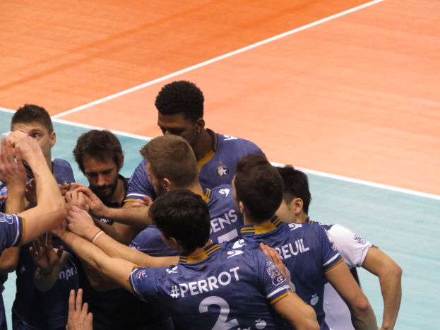 Eine Gruppe von Männern in blauen "Ligue 1"-T-Shirts feiert auf einem Volleyballfeld.