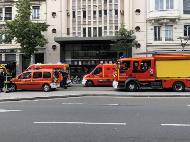 Eine Gruppe von Feuerwehrautos auf einer Straße in Paris geparkt, mit Menschen in der Nähe, vor Gebäuden, Bäumen und einem Fahrrad