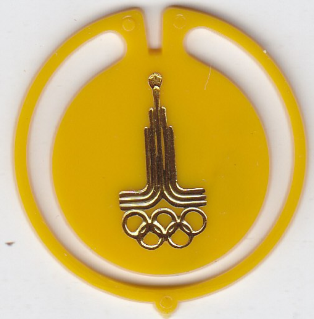 Gelbes rundes Olympia-Abzeichen mit goldenen Ringen-Logo auf einem weißen Hintergrund.