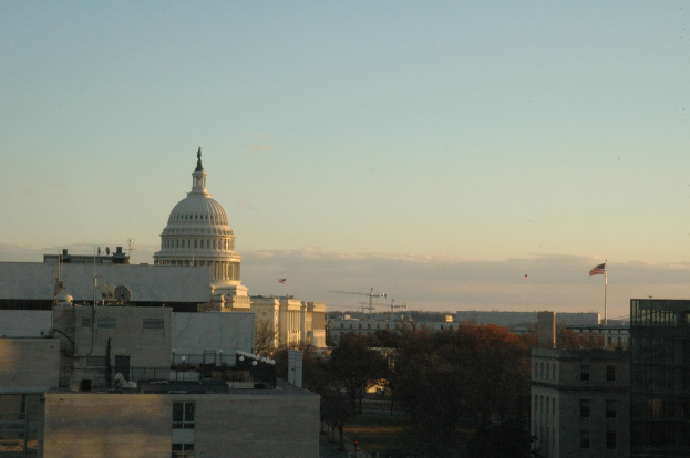 Eine Stadtansicht mit Gebäuden, Bäumen, Fahnen unter einem Himmel, mit einer Straße unten.