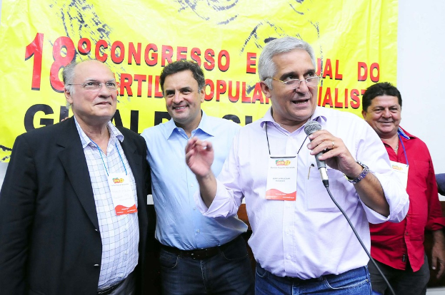 Ein Mann spricht in ein Mikrofon vor einem gelben Vorhang mit der Aufschrift "18. Kongress o"