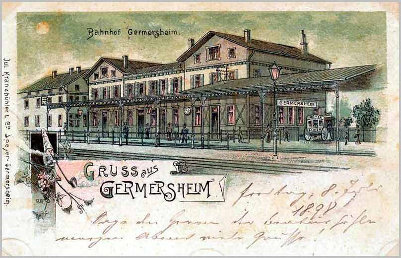 Alte Postkarte des Bahnhofs Germersheim in Deutschland, die ein Gebäude mit Fenstern, einen Zaun, einen Laternenpfahl, Menschen, Fahrzeuge, Bäume und einen bewölktem Himmel zeigt.