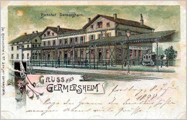 Alte Postkarte des Bahnhofs Germersheim in Deutschland, die ein Gebäude mit Fenstern, einen Zaun, einen Laternenpfahl, Menschen, Fahrzeuge, Bäume und einen bewölktem Himmel zeigt.