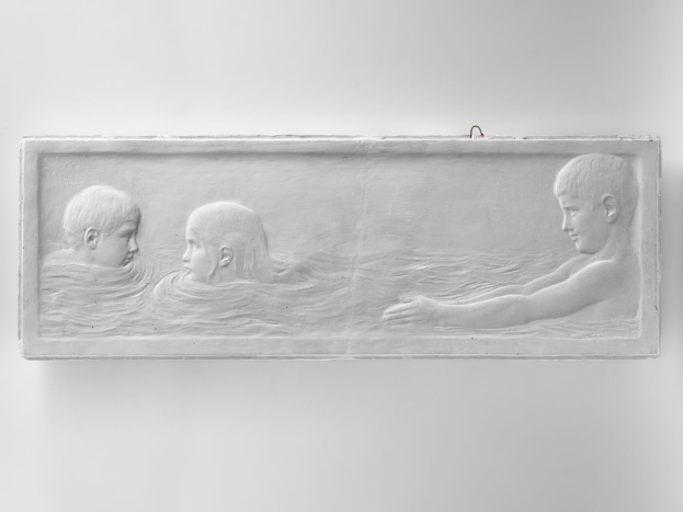 Drei Kinder schwimmen im Wasser, mit einer Wand im Hintergrund, dargestellt in einem Schwarz-Weiß-Foto.