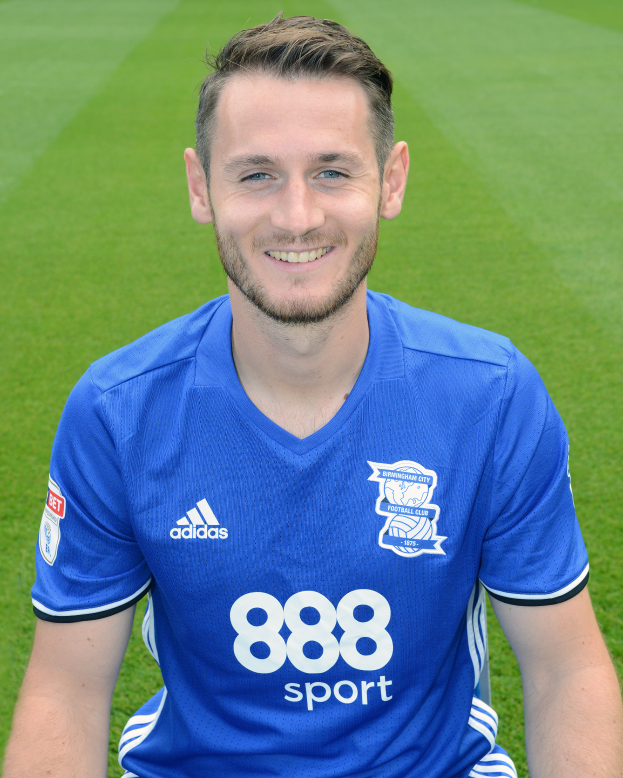 Ein Mann sitzt auf einem Fußballfeld in einem blauen T-Shirt und lächelt, mit Text unten, der eine Trainingseinheit anzeigt.