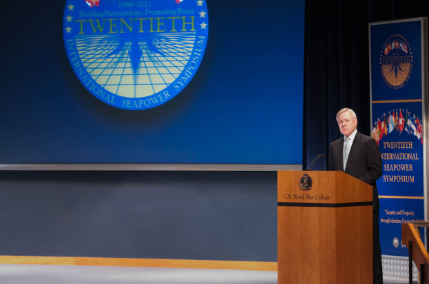 US-Außenminister Mike Pompeo, gekleidet in eine schwarze Jacke, weißes Hemd und schwarze Krawatte, steht an einem Podium mit zwei Mikrofonen, spricht bei der 20. Internationalen Seapower Symposium vor einem blauen Hintergrund und einem Geländer auf der rechten Seite.
