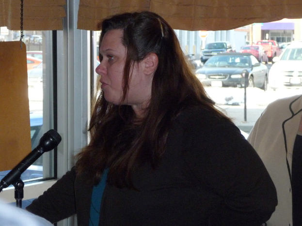 Eine Frau spricht mit einer anderen Person hinter sich, mit einem Fenster, das mehrere Fahrzeuge zeigt.