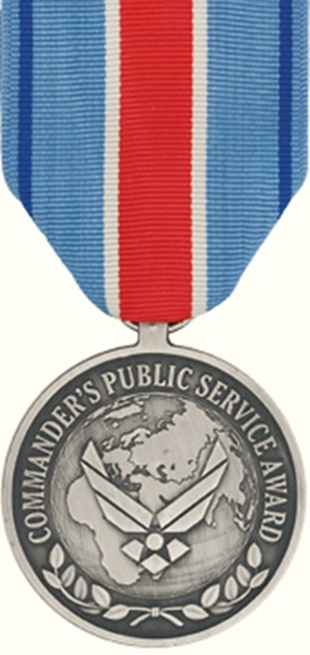 Eine Silbermedaille mit einer rot-weiß-blauen Schleife, auf der die Wörter 'Commander's Public Service Award' gegen einen weißen Hintergrund geschrieben stehen.
