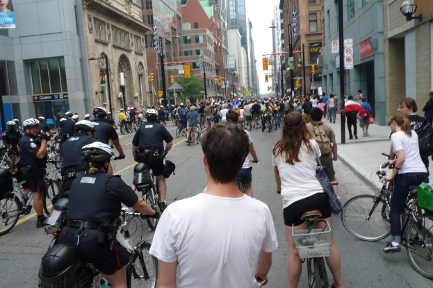 Gebäude säumen eine Straße, auf der wenige Menschen Fahrräder fahren.