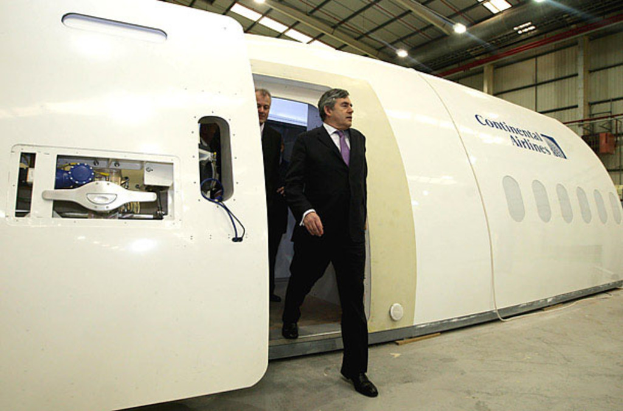 Ein Flugzeug-Prototyp mit "Continental Airlines" darauf, mit zwei Personen daneben, vor einem Hintergrund aus einer Wand, Lichtern und ein paar anderen Gegenständen.