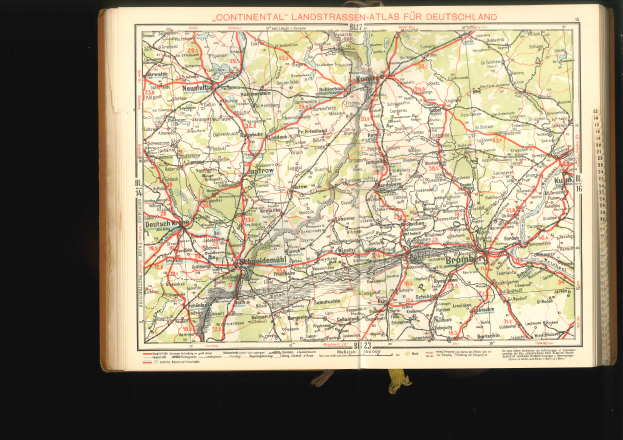 Ein aufgeschlagenes Buch mit einer detaillierten Deutschlandkarte mit Straßen und Autobahnen auf schwarzem Hintergrund.