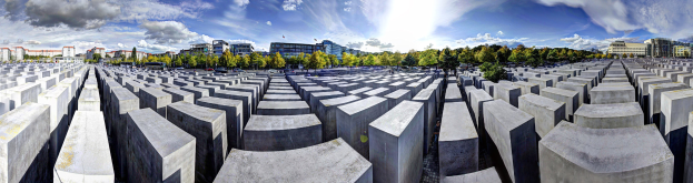 Luftaufnahme des Holocaust-Mahnmals für die ermordeten Juden Europas in Berlin, Deutschland, mit großen Betonsteinen, umgeben von Bäumen, Gebäuden und Fahrzeugen mit einer bewölkten Himmel.